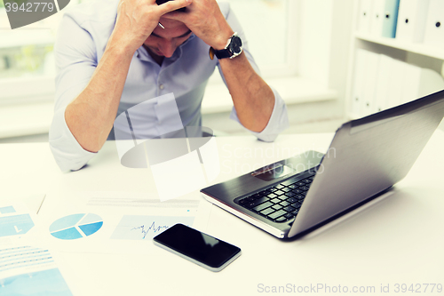 Image of businessman with laptop and papers in office