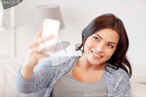 Image of happy woman taking selfie with smartphone at home