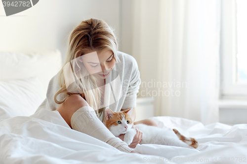 Image of happy young woman with cat in bed at home