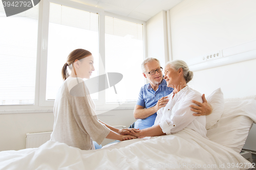 Image of happy family visiting senior woman at hospital