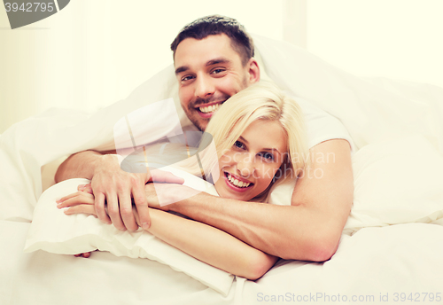 Image of happy couple lying in bed and hugging at home