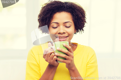 Image of happy african american woman drinking from tea cup