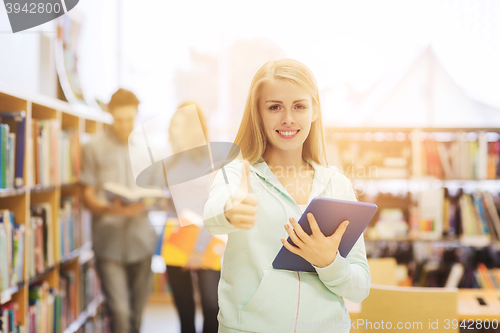 Image of happy student girl with tablet pc in library