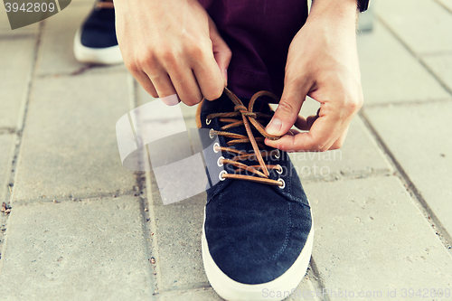 Image of close up of male hands tying shoe laces on street