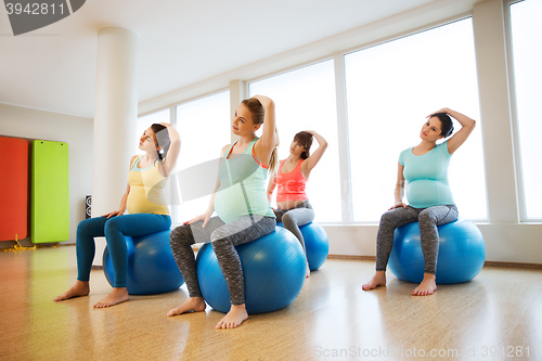 Image of happy pregnant women exercising on fitball in gym