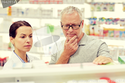 Image of pharmacist showing drug to senior man at pharmacy