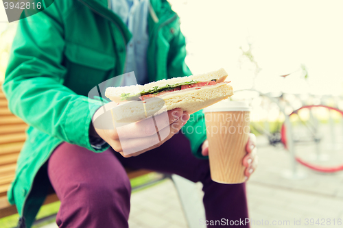 Image of close up of man with coffee and sandwich on street