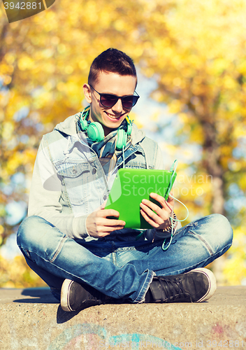 Image of happy young man with tablet pc and headphones