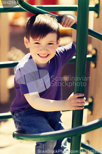 Image of happy little boy climbing on children playground