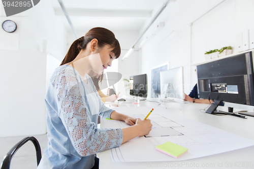 Image of architect woman drawing on blueprint at office