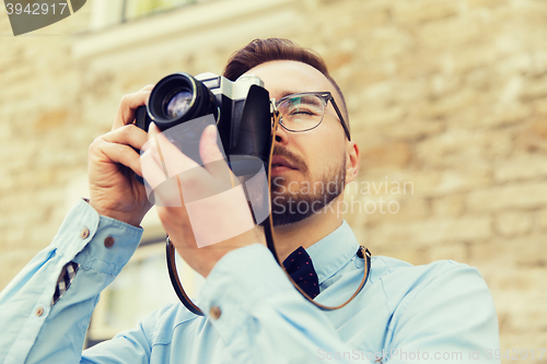 Image of young hipster man with film camera in city