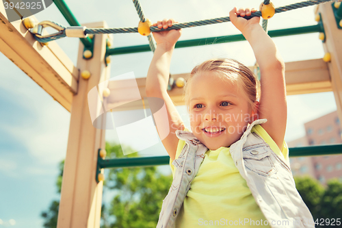Image of happy little girl climbing on children playground
