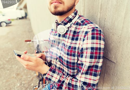 Image of hipster man in earphones with smartphone and bike