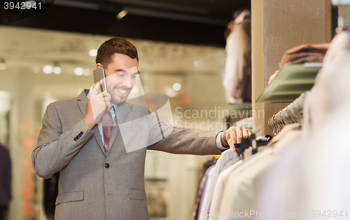 Image of happy man calling on smartphone at clothing store