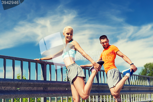 Image of smiling couple stretching outdoors