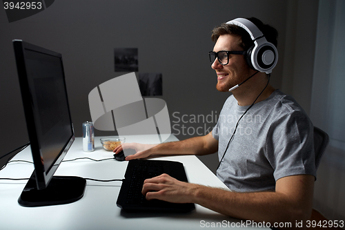 Image of man in headset playing computer video game at home