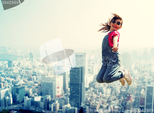 Image of happy little girl jumping over city background