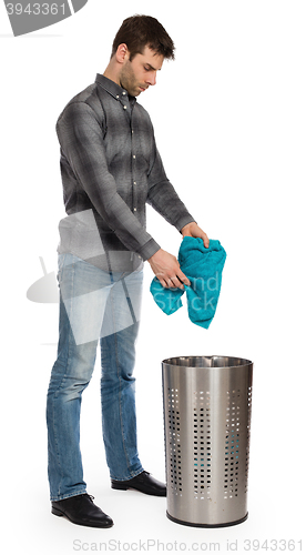 Image of Young man putting a dirty towel in a laundry basket