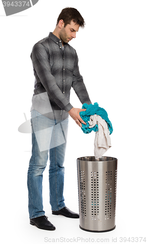 Image of Young man putting a dirty towel in a laundry basket