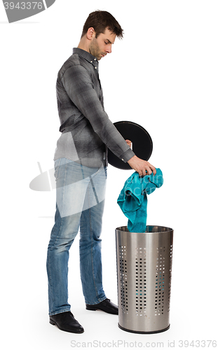 Image of Young man putting a dirty towel in a laundry basket