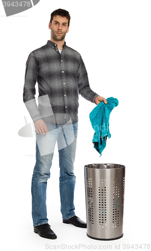 Image of Young man putting a dirty towel in a laundry basket