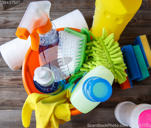 Image of Plastic bucket with cleaning supplies on wood background