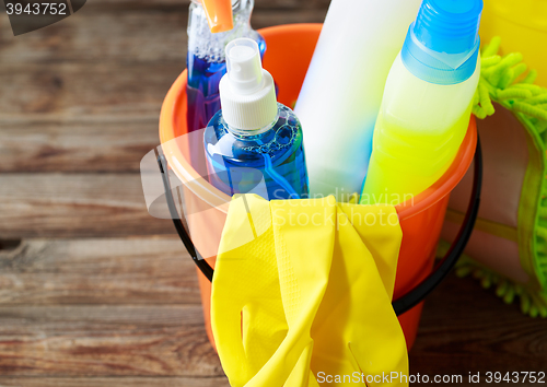 Image of Plastic bucket with cleaning supplies on wood background