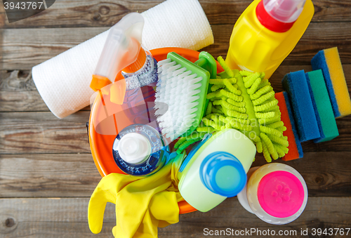 Image of Plastic bucket with cleaning supplies on wood background