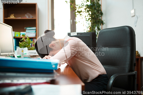 Image of Tired businesswoman sleeping on the desk.