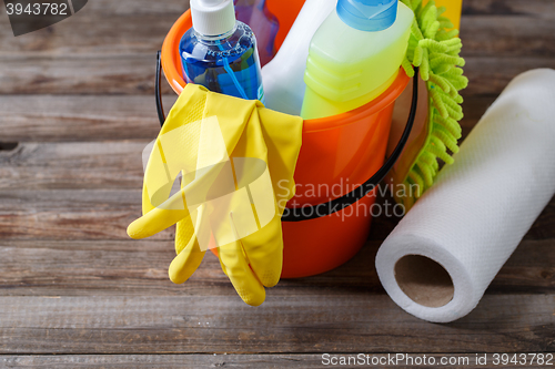 Image of Plastic bucket with cleaning supplies on wood background