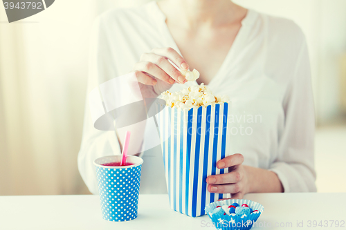 Image of woman eating popcorn with drink and candies