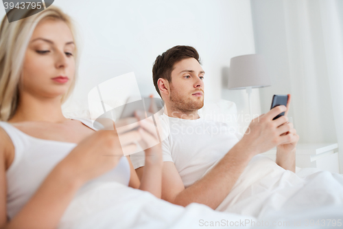 Image of couple with smartphones in bed