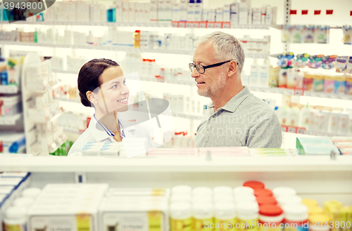 Image of happy pharmacist talking to senior man at pharmacy