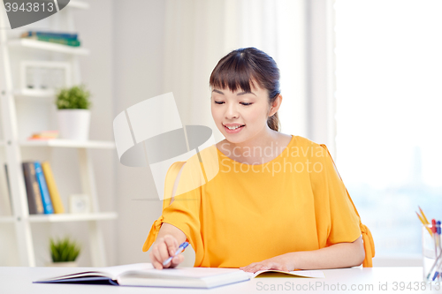 Image of happy asian young woman student learning at home