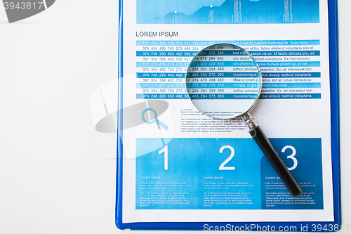 Image of close up of financial report and magnifying glass