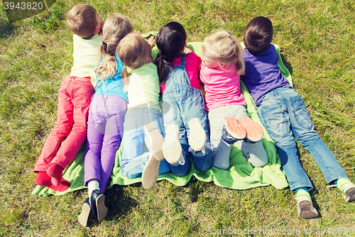 Image of group of kids lying on blanket or cover outdoors