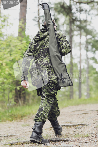 Image of young soldier or hunter with gun in forest