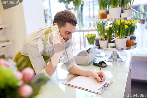 Image of man with smartphone making notes at flower shop