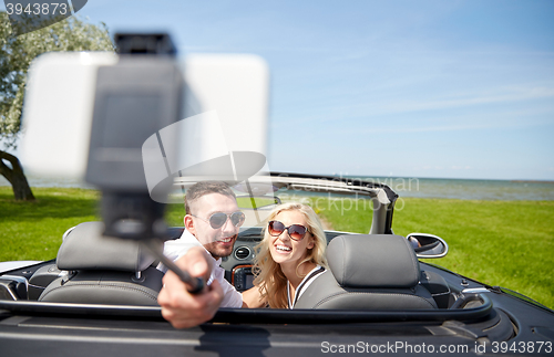 Image of happy couple in car taking selfie with smartphone