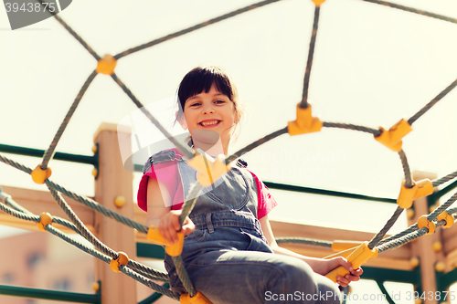 Image of happy little girl climbing on children playground