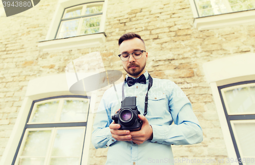 Image of happy young hipster man with film camera in city