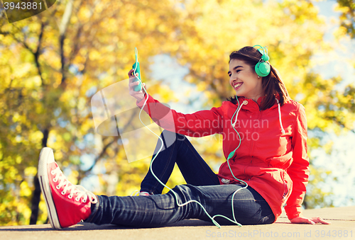 Image of happy young woman with smartphone and headphones