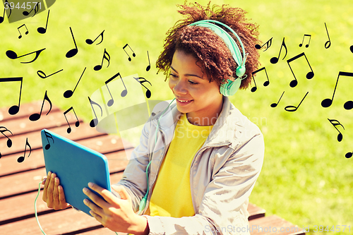 Image of happy african woman in headphones with tablet pc