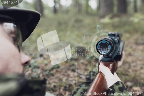 Image of close up of soldier or sniper with gun in forest
