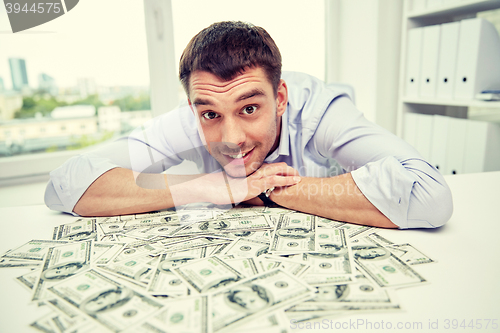 Image of happy businessman with heap of money in office