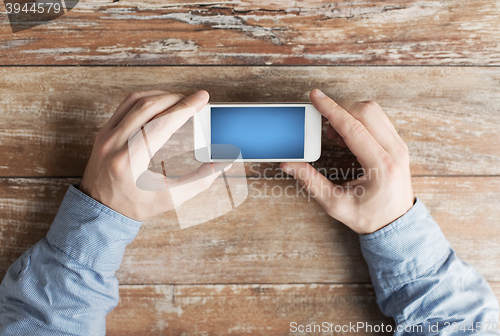 Image of close up of male hands with smartphone on table