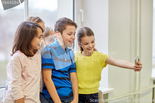 Image of group of school kids taking selfie with smartphone