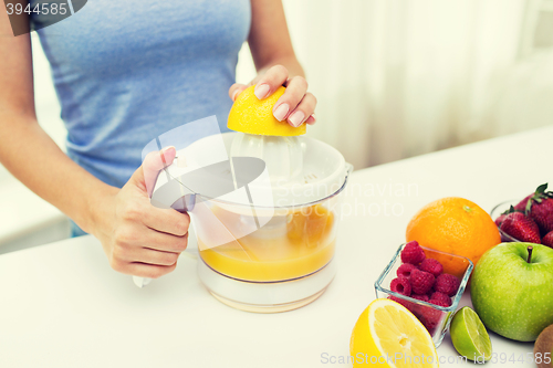 Image of close up of woman squeezing fruit juice at home