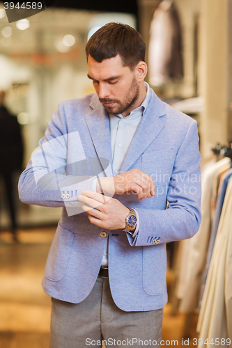 Image of young man trying jacket on in clothing store