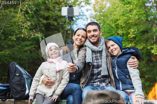 Image of family with smartphone taking selfie near campfire